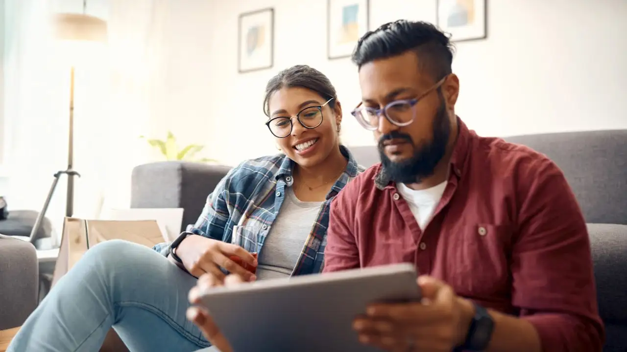 young couple using a digital tablet while relaxing on the couch at home