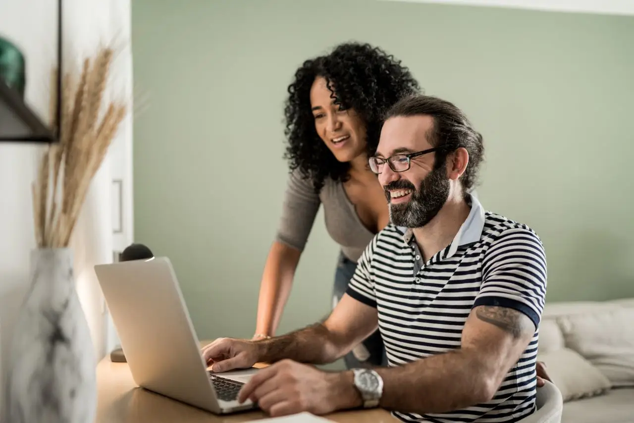 Couple using laptop together at home looking for debt consolidation loan