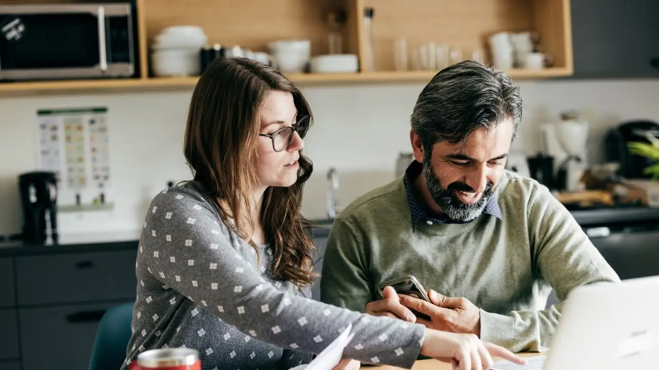 Couple doing financial calculations in kitchen