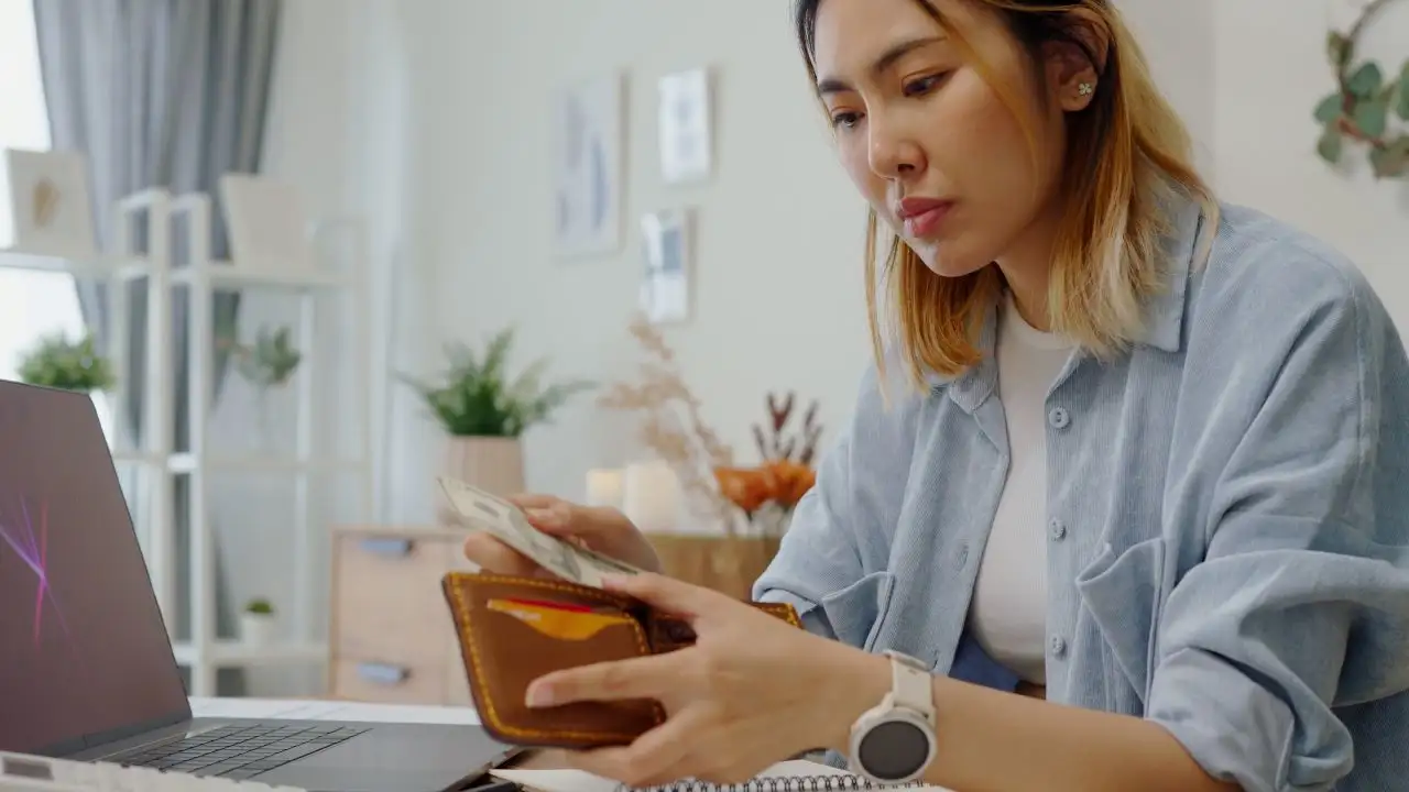 Young woman looking at wallet and considering if she should buy now pay later