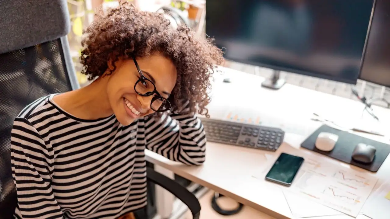 Young woman sitting at desk, smiling after  crushing her debt