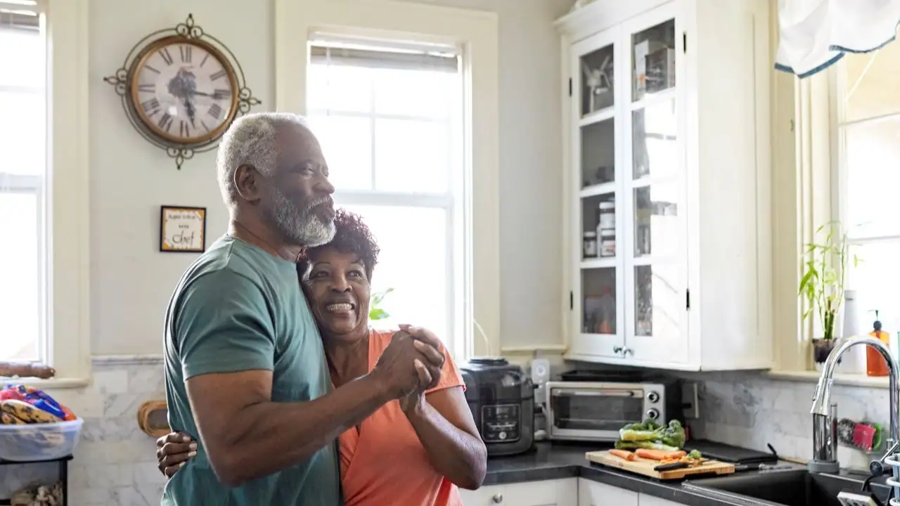 Playful seniors embracing and dancing in kitchen