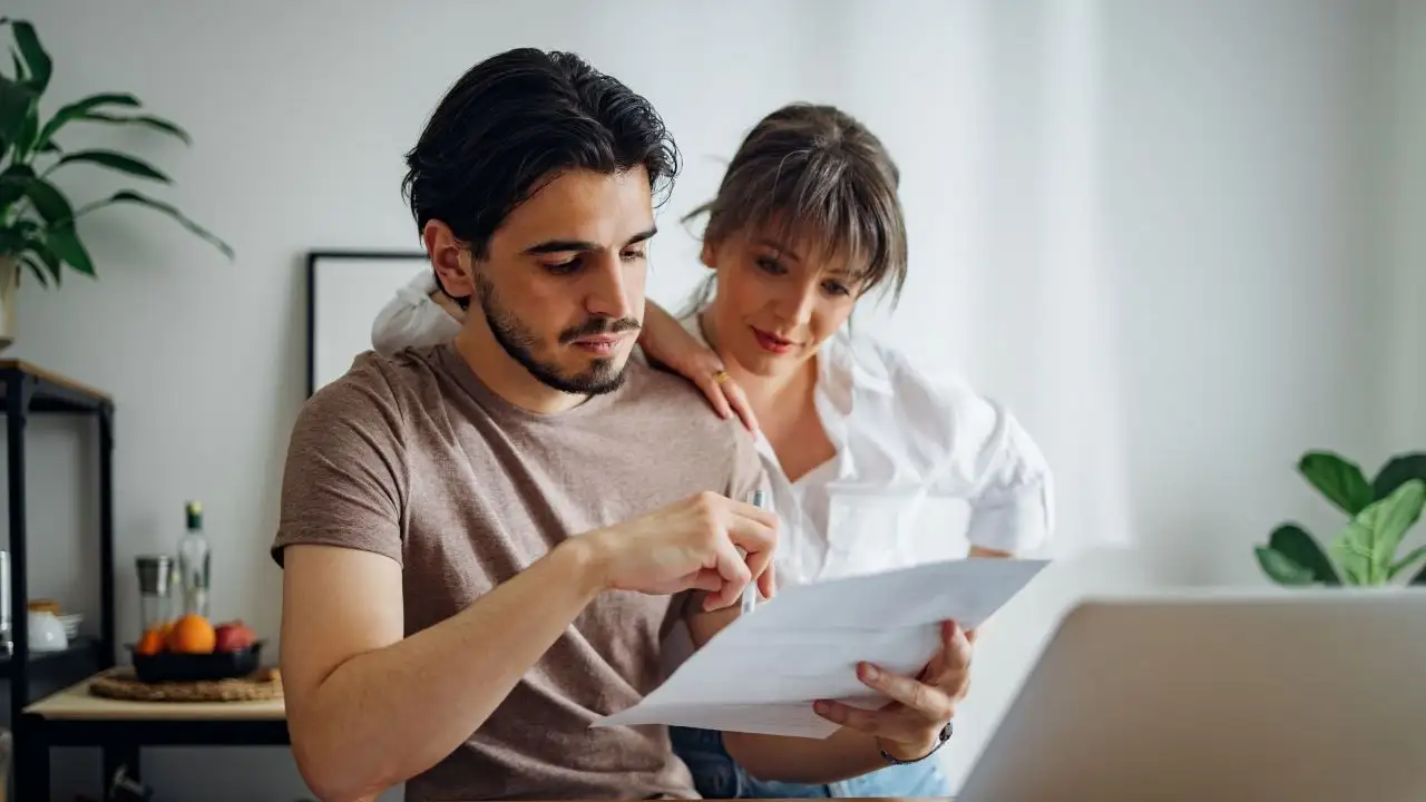 Couple doing home finances together online on a laptop computer in the kitchen.