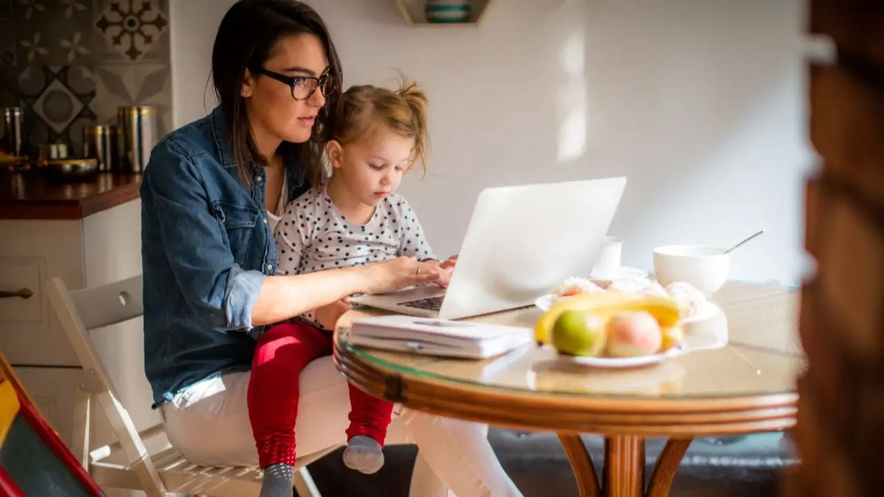 Mother with toddler on lap. The mother is reviewing a personal loan offer.