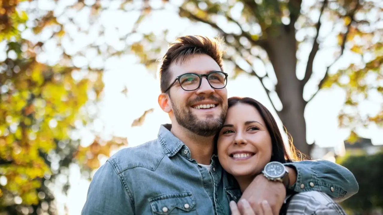 Happy young couple walking in the park contemplating the future