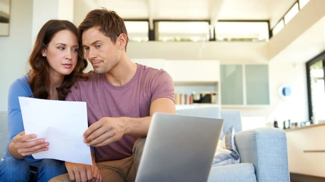 Young couple going through finances while sitting at home in their living room