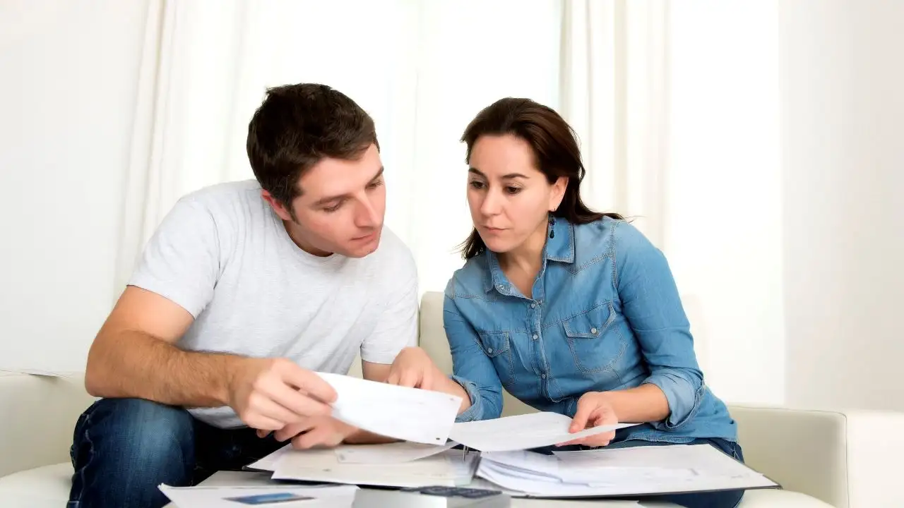 Couple sitting on sofa and reviewing financial documents