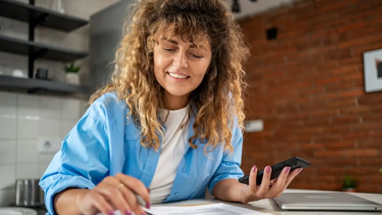 Woman with calculator and dairy checking ways debt consolidation could improve her life