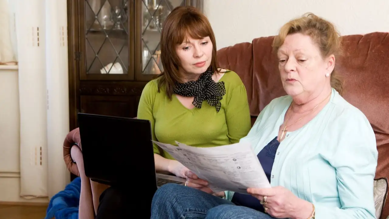 A mature daughter helping her senior mother to keep on top of her household accounts