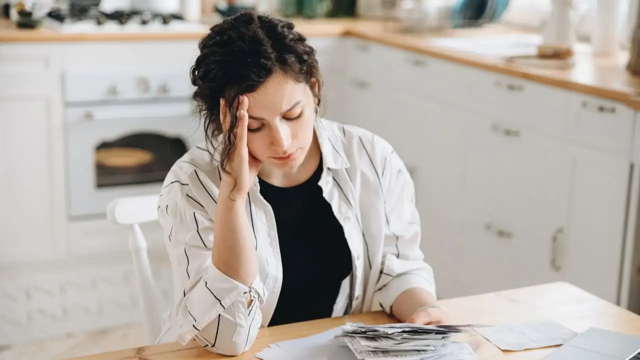 Young woman sitting at kitchen table and trying to figure out much debt she has and can she file bankruptcy