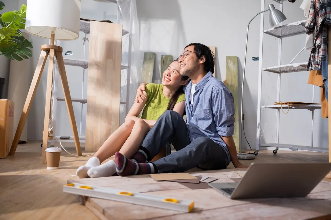 Couple sits on the floor of their home, which is under renovation.