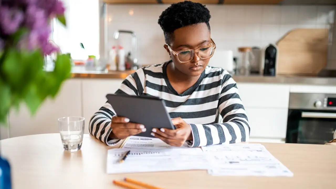 Young woman sits at a table and calculates her expenses