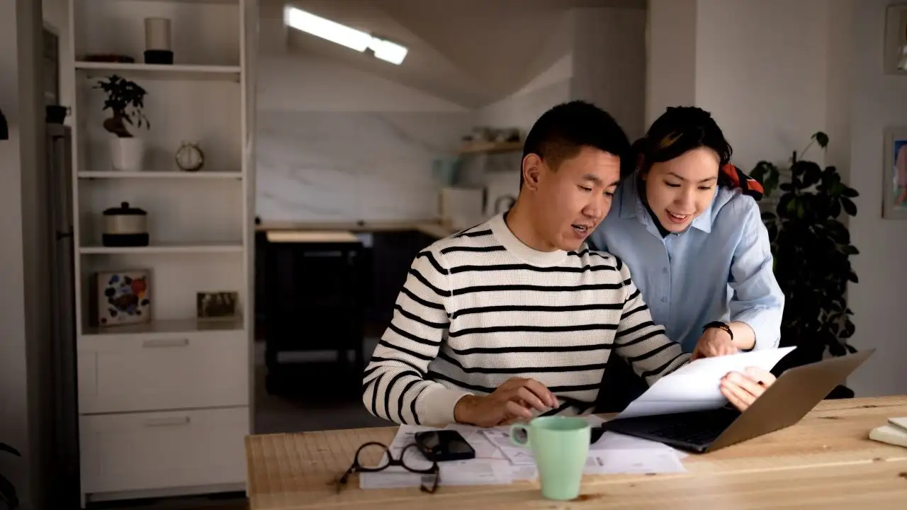 Young couple cooperating while going through their financial bills at home.