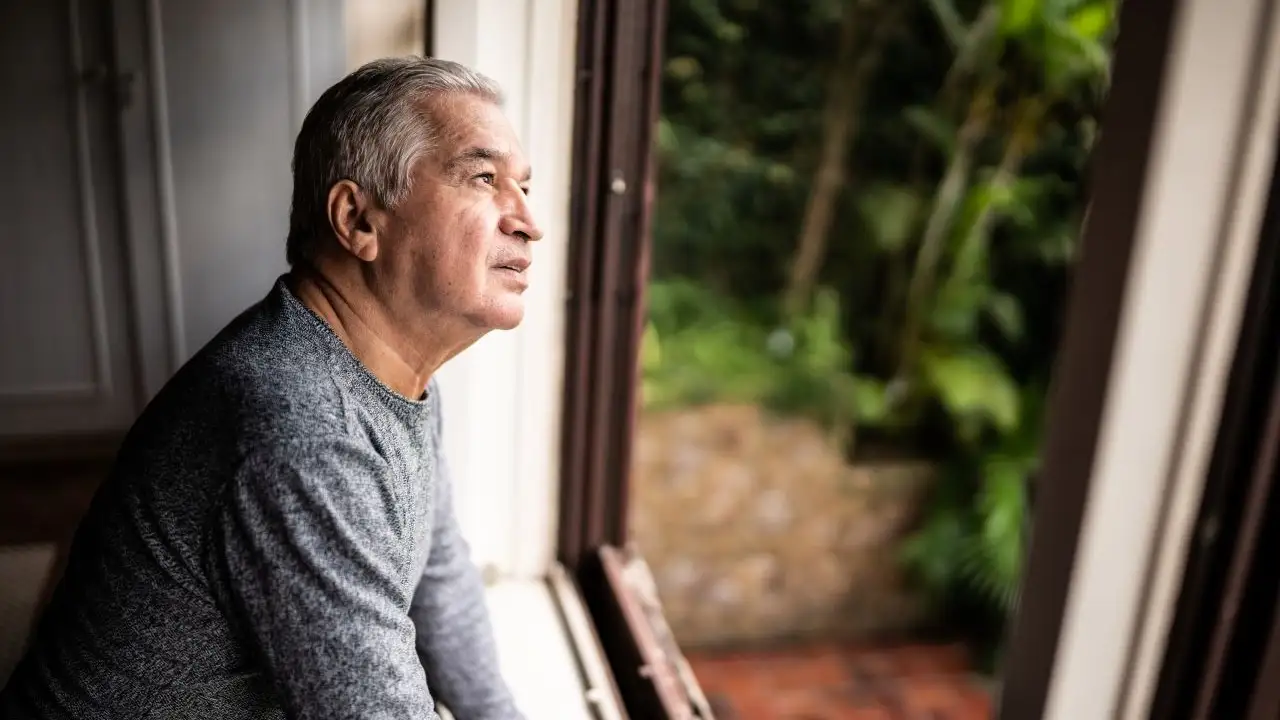 Senior man contemplating looking through the window