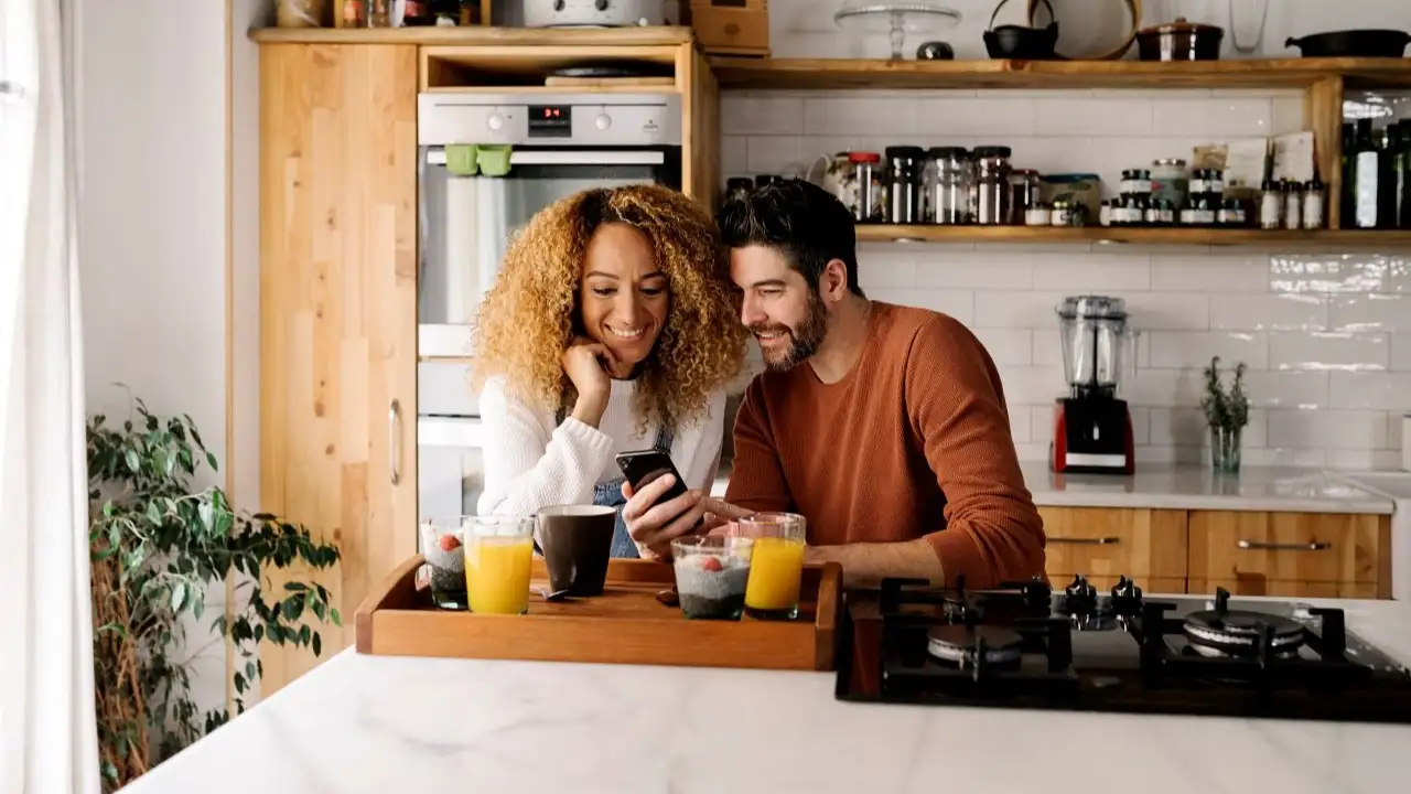 Couple in kitchen reviewing 30-year home equity loan offer on phone app